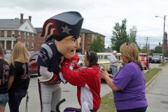 Patriots' Mascot having a picture taken holding a baby.